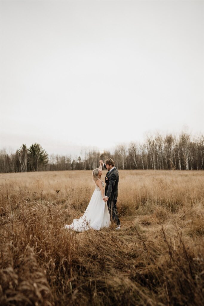 groom picking up bride in grassy field at ivy black 