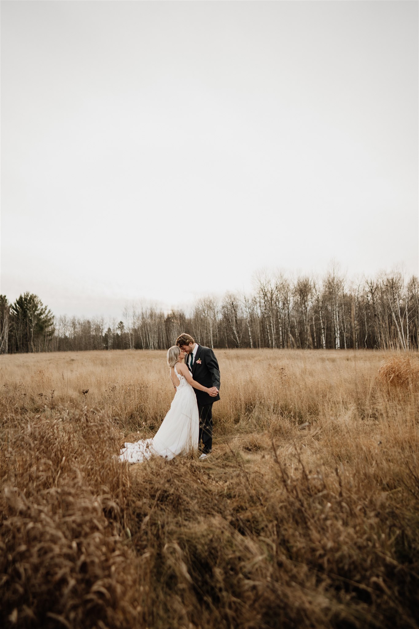 groom picking up bride in grassy field at ivy black 